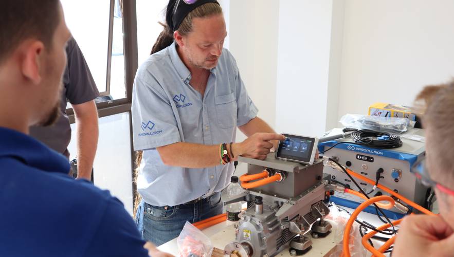 A technical instructor demonstrates the digital interface on a marine electric motor to a group of trainees